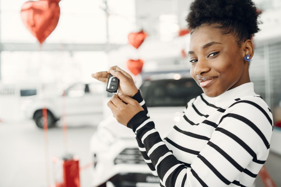 Young driver holding car keys after finding the best first car at a dealership